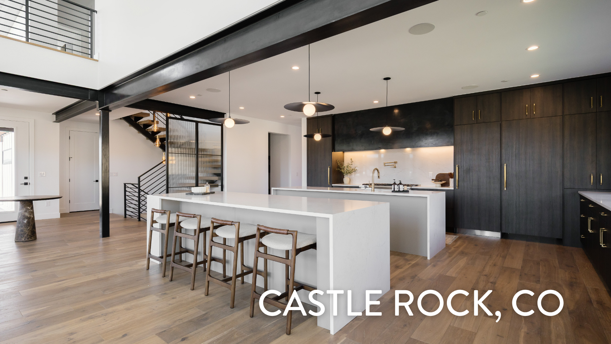 Modern kitchen with dark cabinetry, white waterfall islands, and brass pendant lighting in a luxury home at 5292 Lions Paw St, Castle Rock, CO