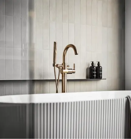 Luxurious fluted soaking bathtub in modern new home with gold faucet and steel shelving.