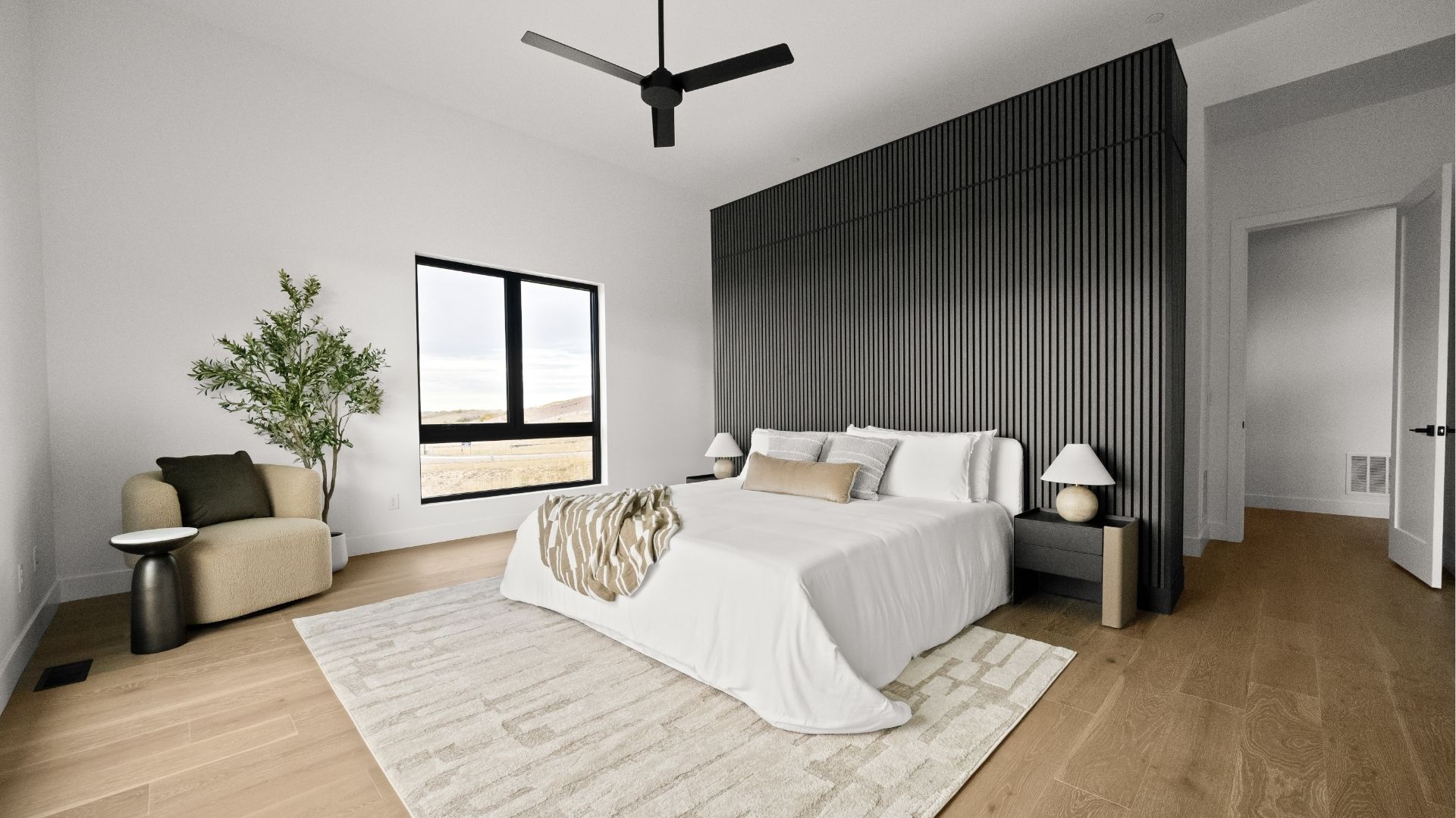 Spacious primary bedroom with custom wood slat wall and valley views in Castle Rock ranch