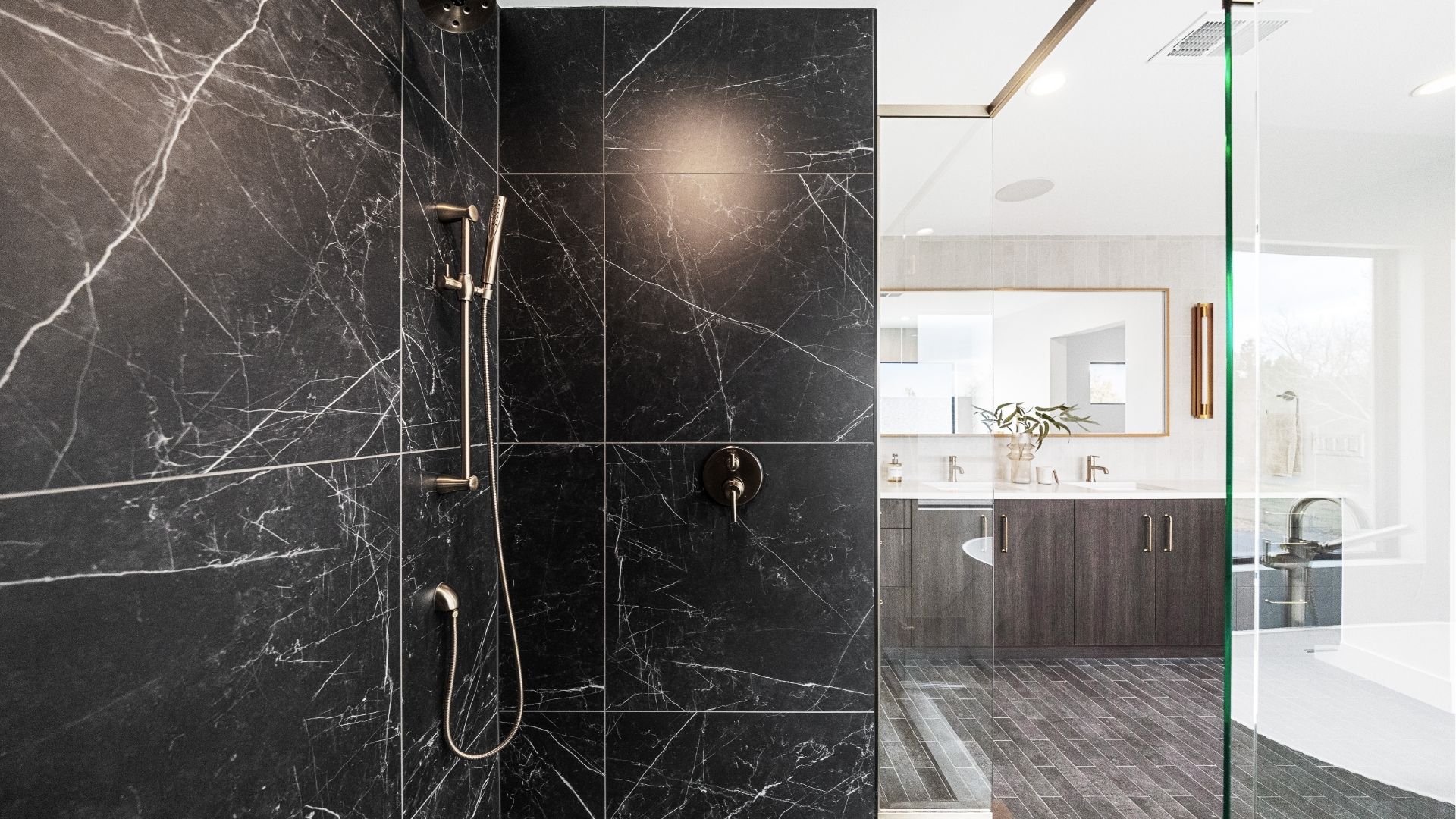Frameless glass shower with quartz tile and gold fixtures in Golden primary bathroom