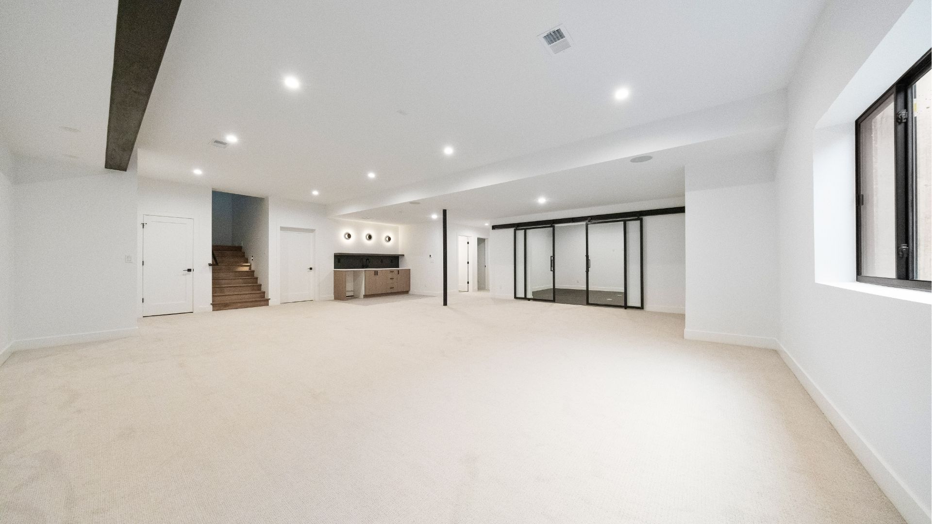 Finished basement with wet bar, gym space, and custom steel glass partition in Golden luxury home