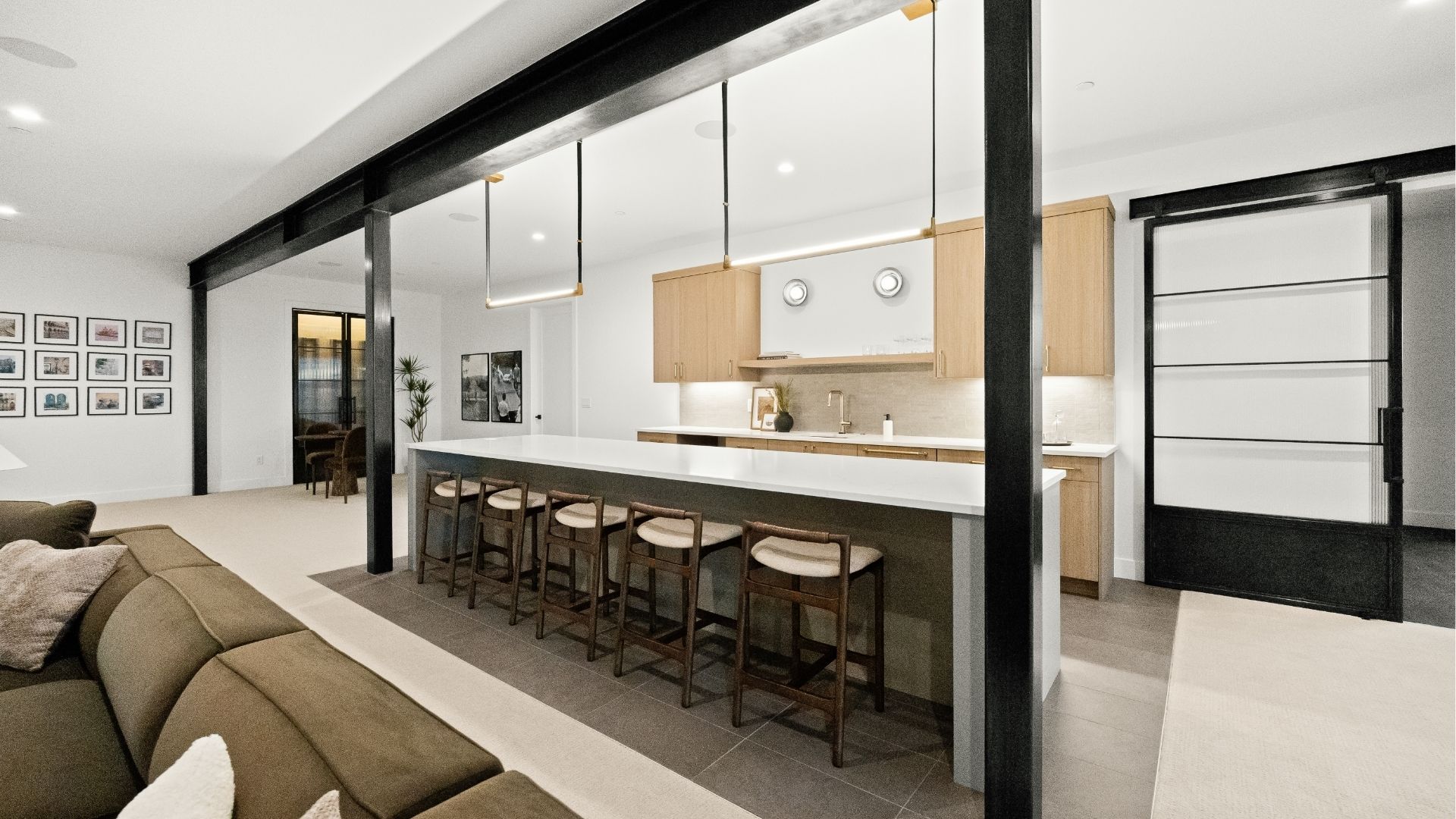 Basement wet bar with light wood cabinetry and steel beam accents in Castle Rock home