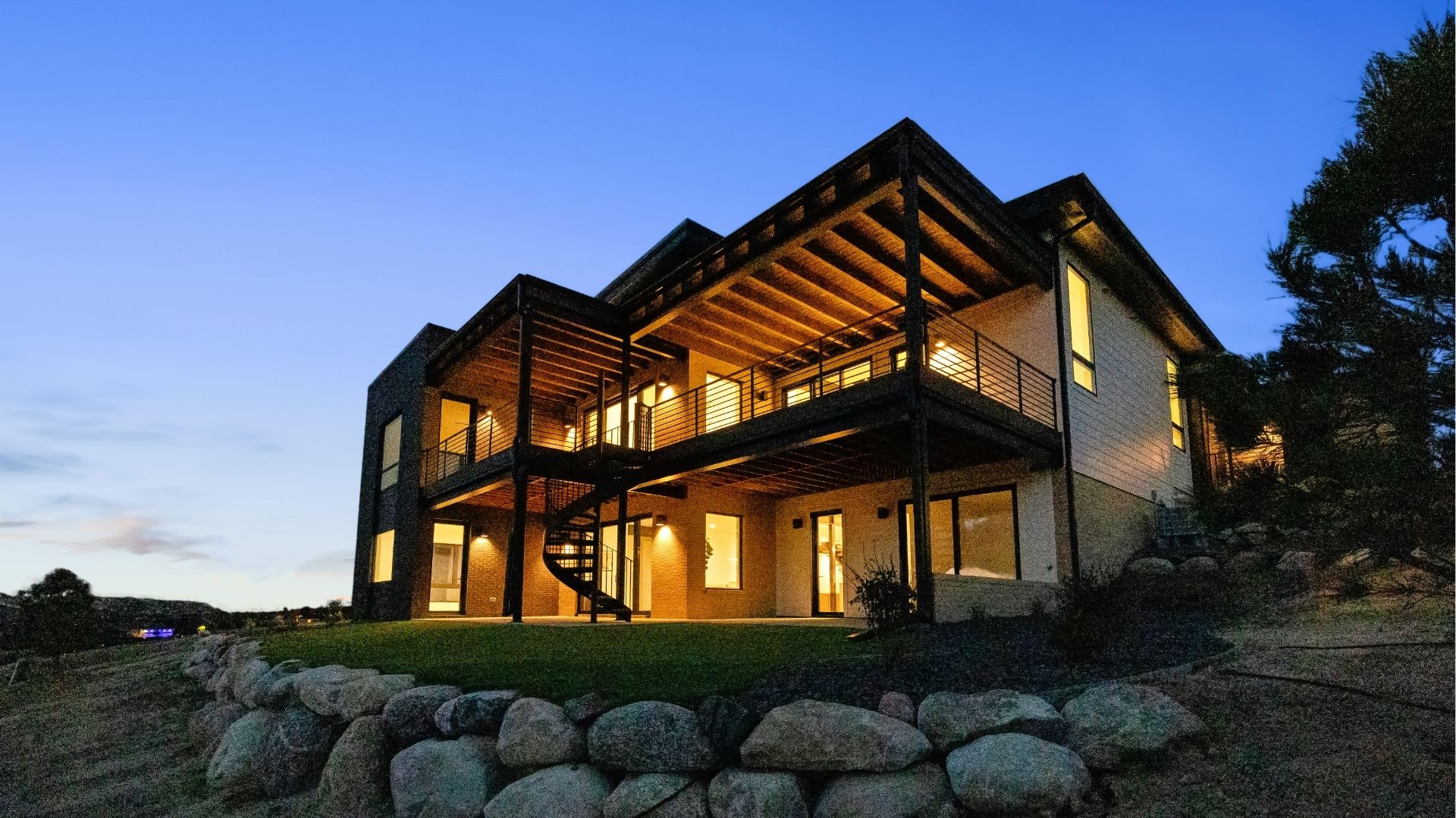Walkout ranch with covered deck and spiral staircase at twilight in Castle Rock Colorado