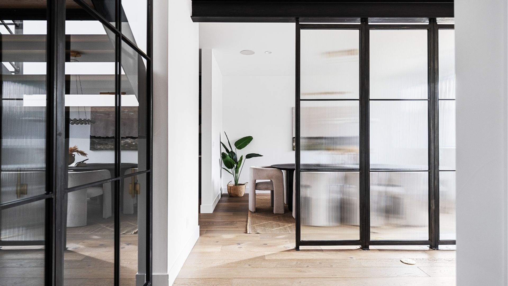 Steel and reeded glass partition separating dining room in modern Golden home