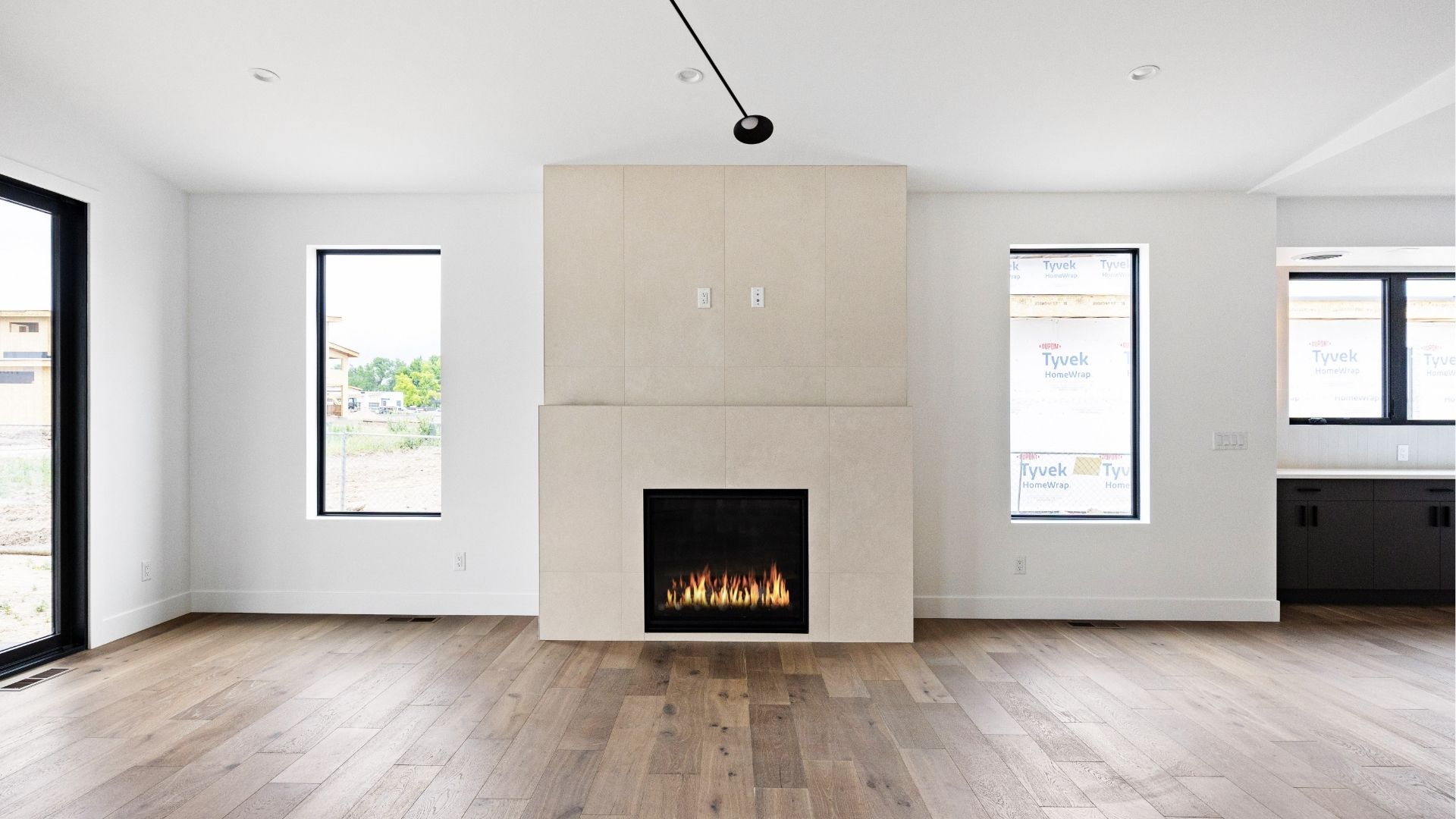 Contemporary great room with floor-to-ceiling fireplace and wood flooring in Golden luxury home