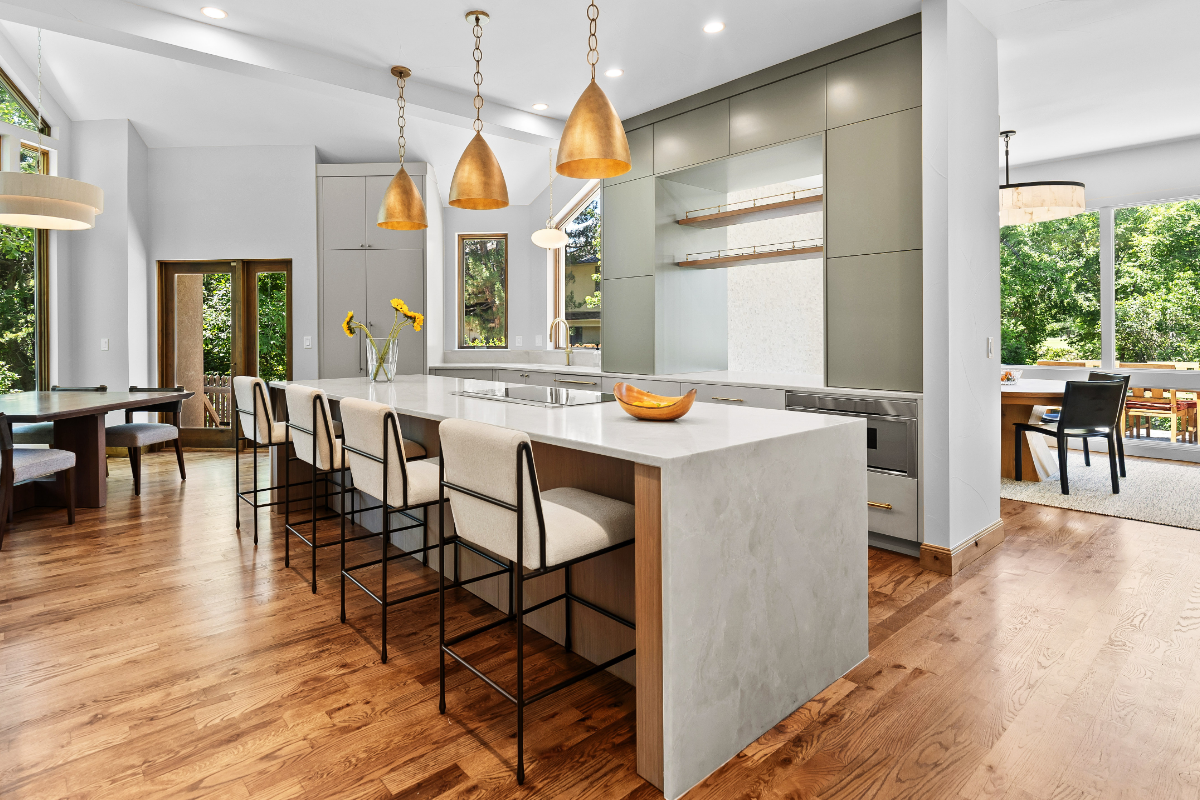 Newly renovated modern kitchen with sage green cabinetry, waterfall quartz island, brass pendant lights, and white oak hardwood floors in Boulder, CO