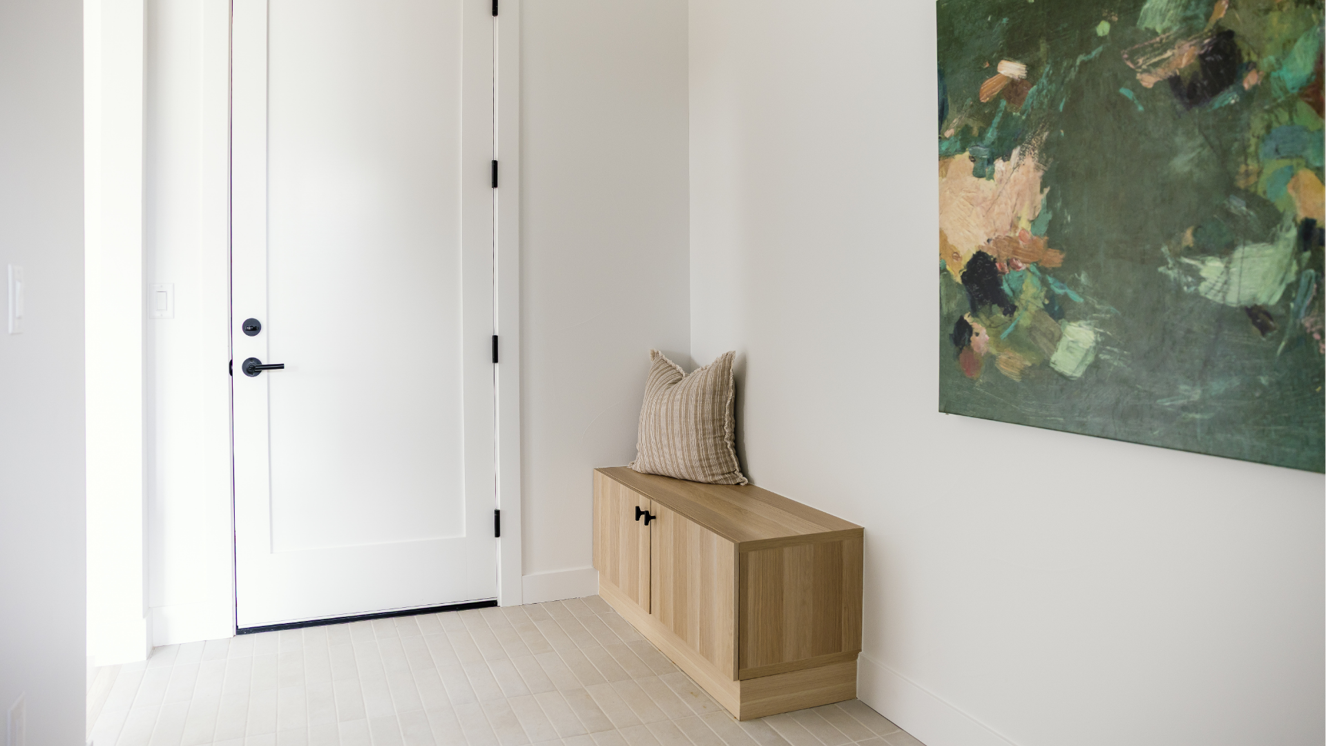 Mudroom with built-in bench, striped throw pillow, and large abstract green painting