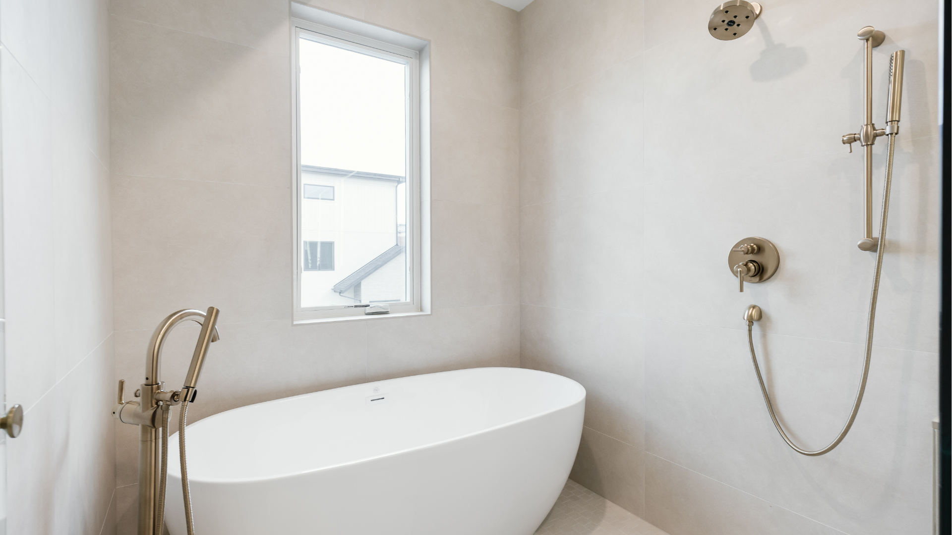 Freestanding soaking tub beside a walk-in shower with brass fixtures