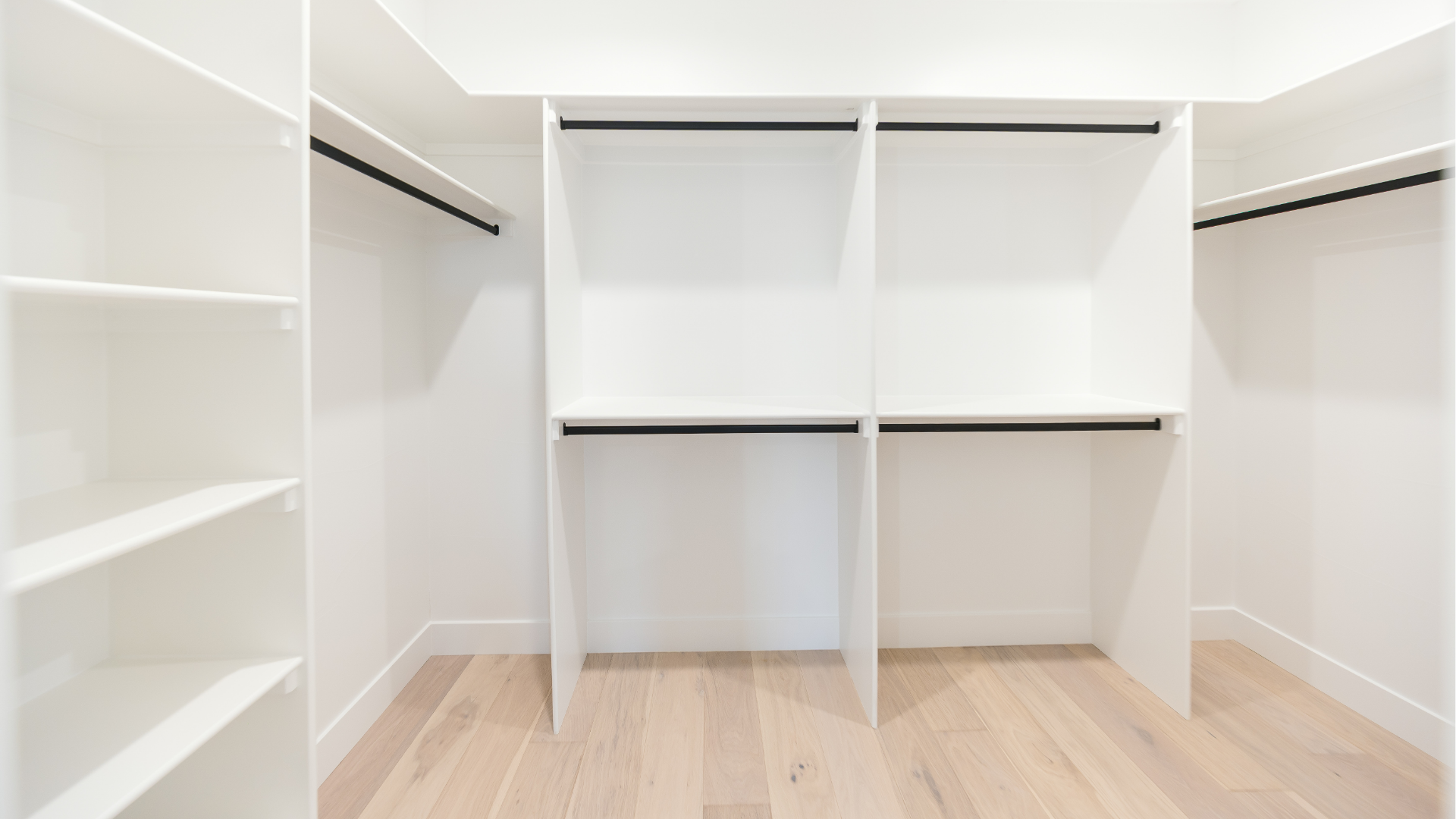 Walk-in closet with built-in white shelving and hanging rods