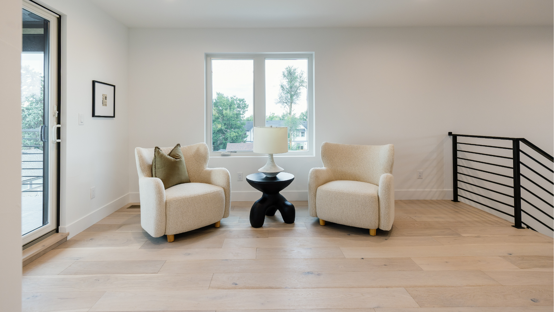 Upstairs sitting nook with two boucle accent chairs, sculptural side table, and balcony door
