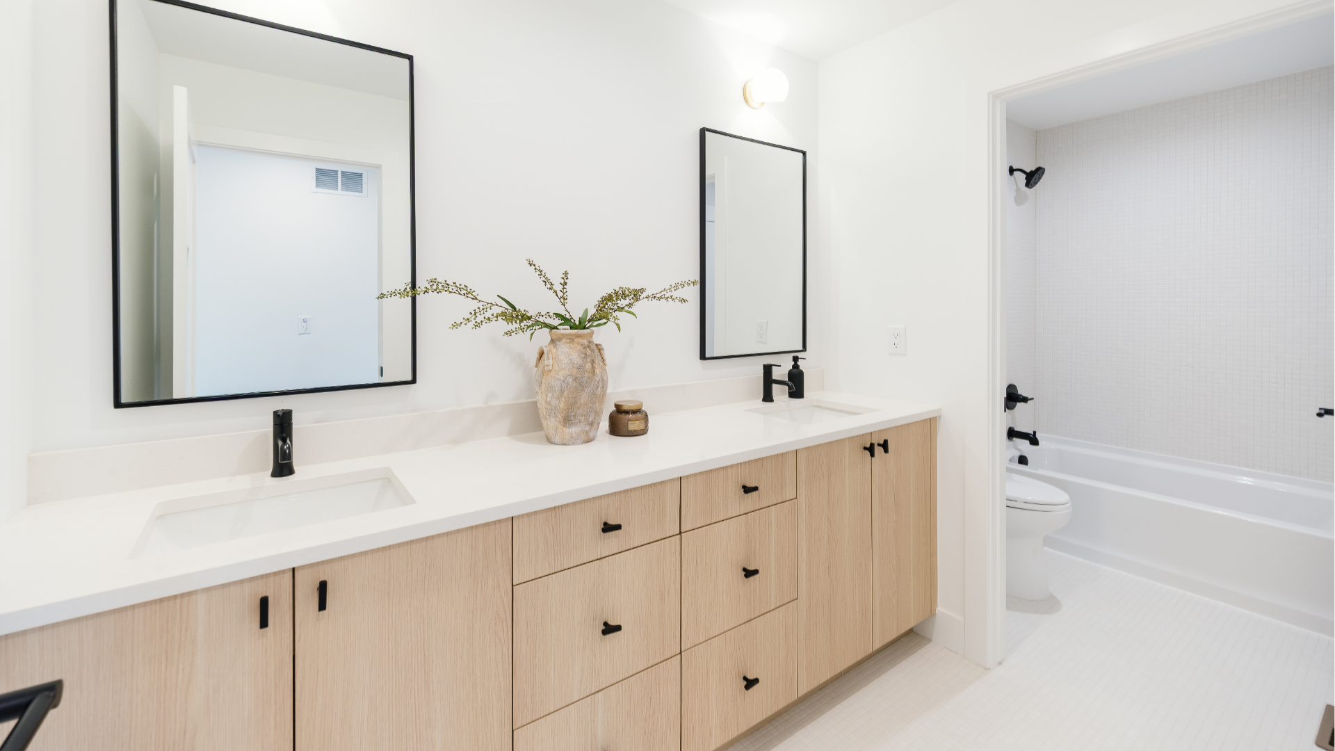 Secondary bathroom with double vanity, black fixtures, and separate tiled tub/shower room