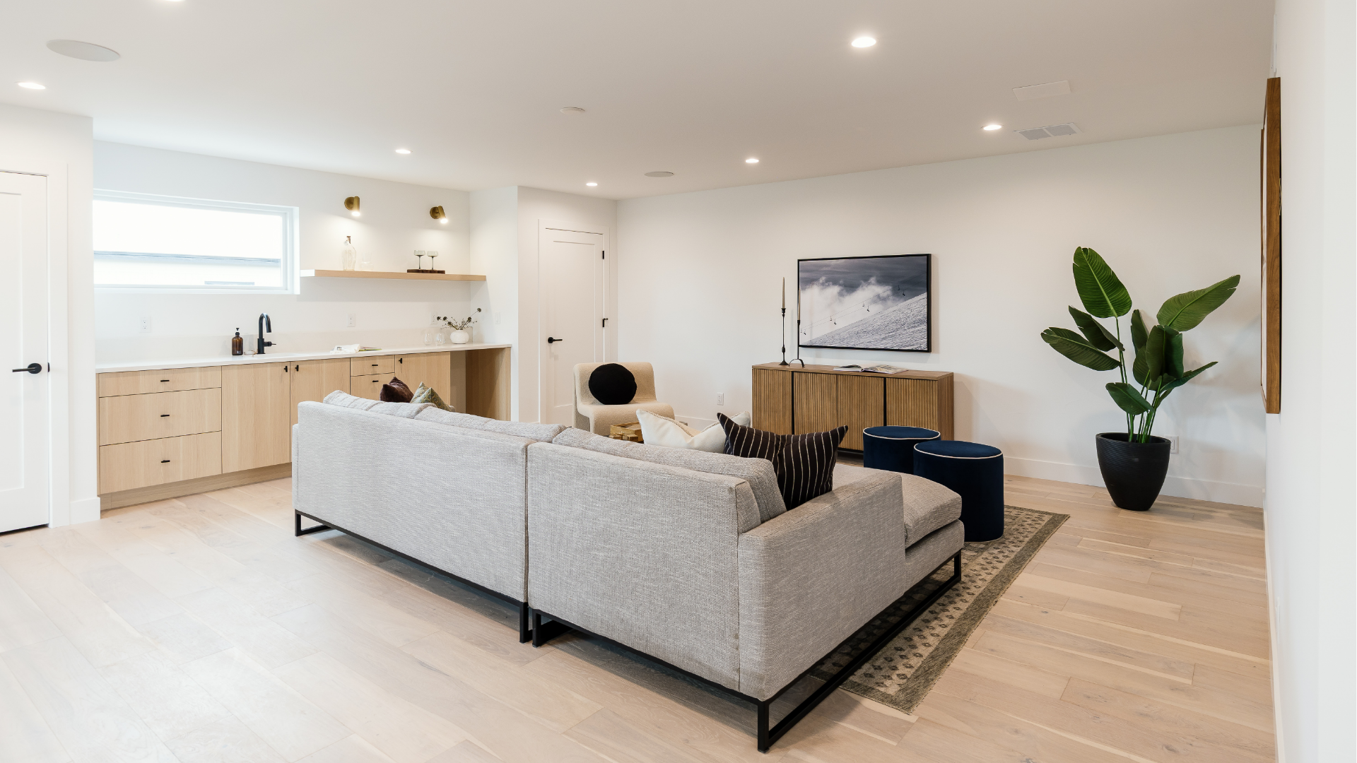 Third-floor loft with gray sectional sofa, wall-mounted TV, and built-in wet bar