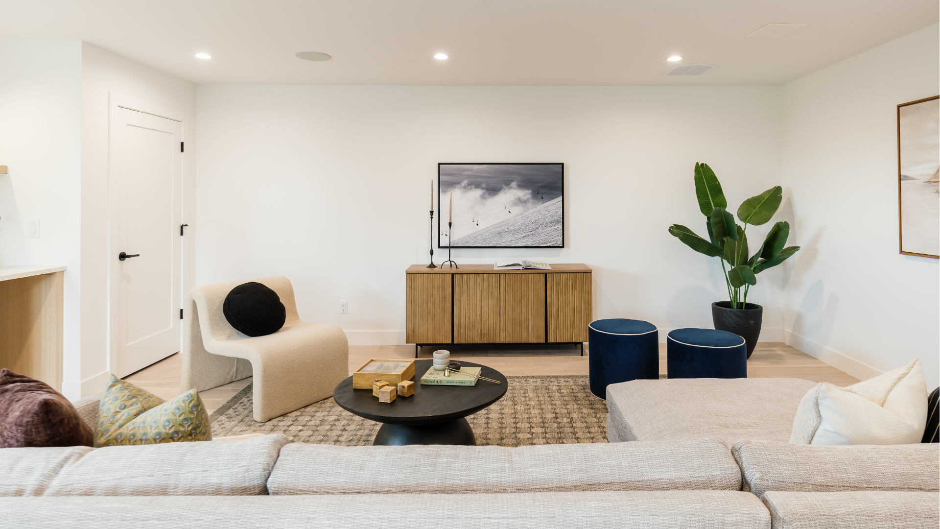 Loft seating area with wood credenza, mounted TV, and navy velvet ottomans