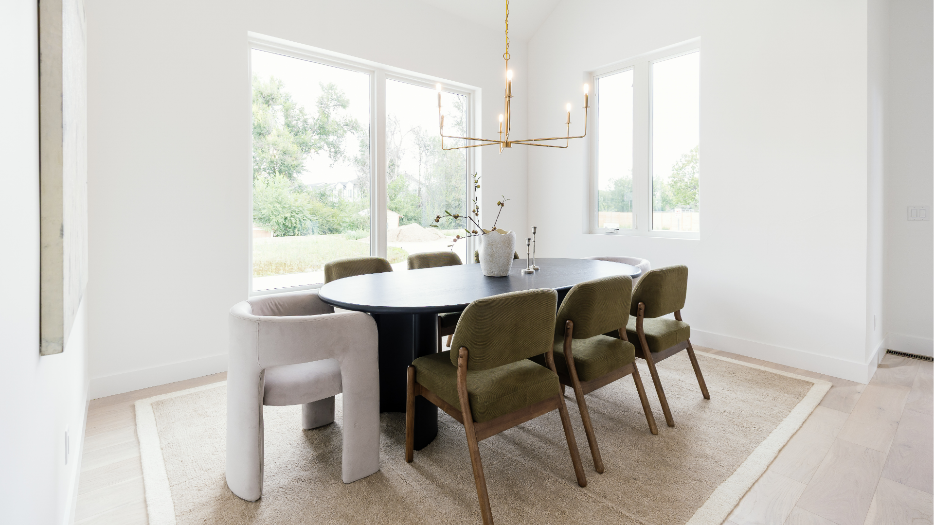 Dining room with black pedestal table, curved cream chairs, and floor-to-ceiling corner windows
