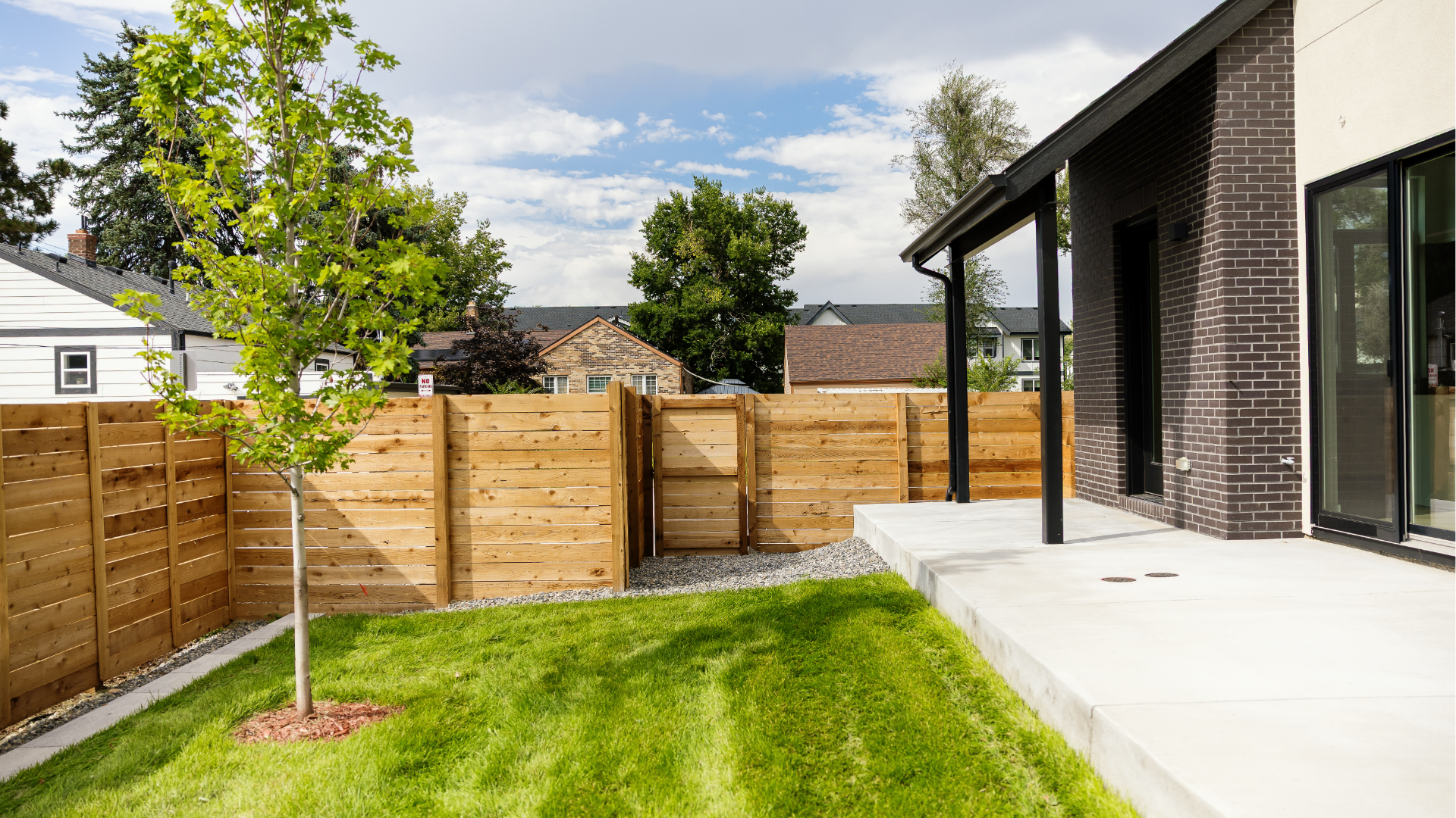 Fenced backyard with cedar privacy fence, gate, and covered concrete patio