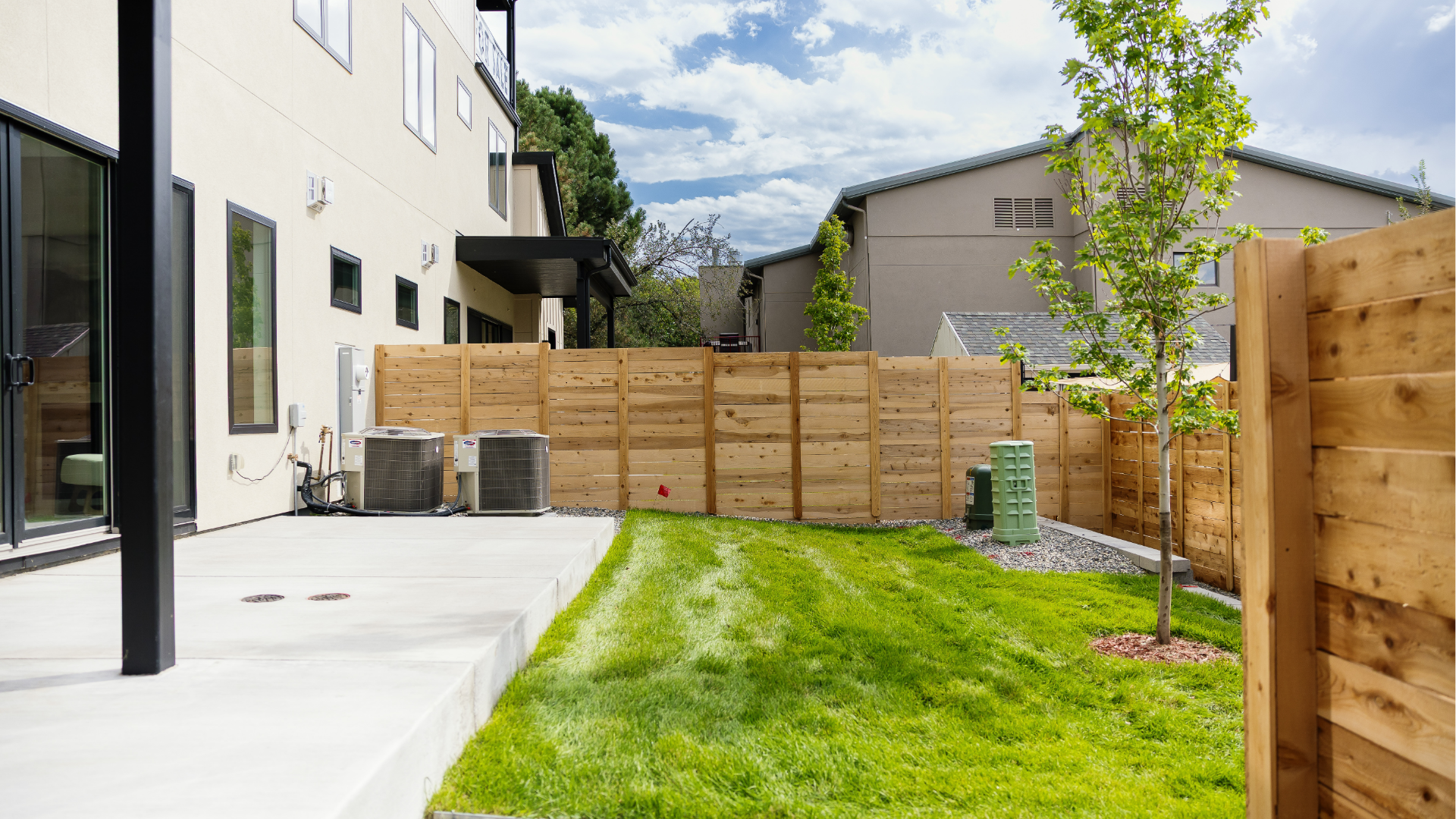Backyard concrete patio and grass area enclosed by cedar fencing