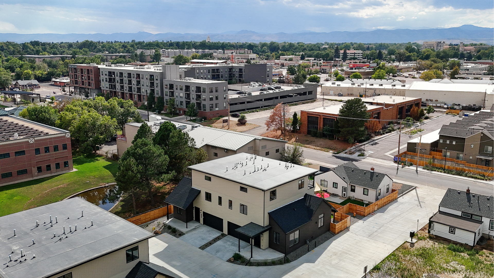 Aerial drone view of a duplex in Wheat Ridge, CO, surrounded by mature trees with mountain views in the background