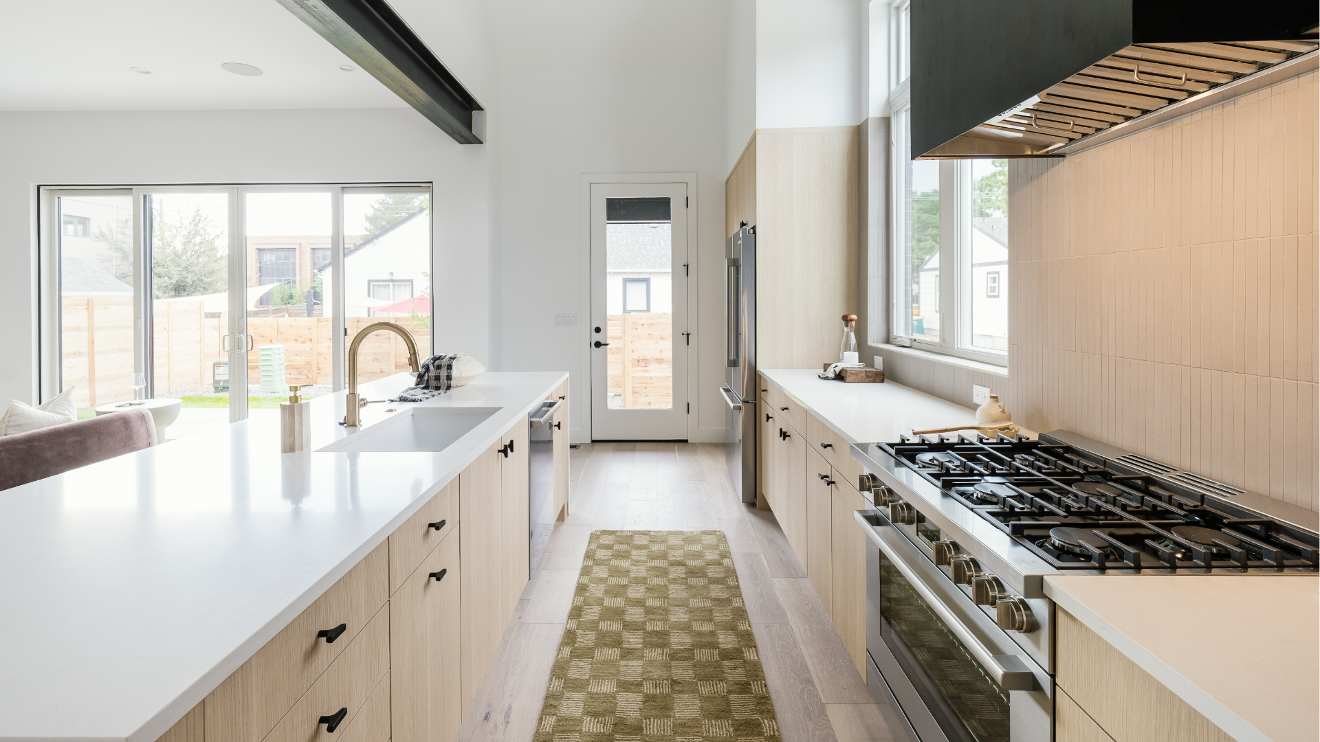Galley-style kitchen with professional gas range, wood cabinetry, and glass door to the backyard